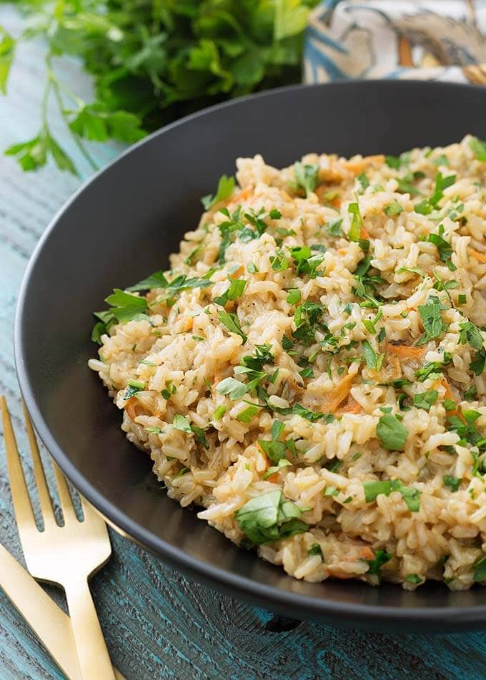 Brown Rice Pilaf in a black bowl next to two golden forks