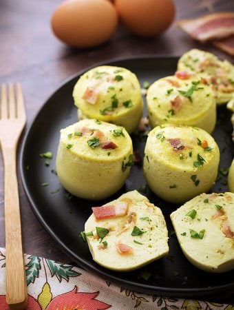 Several Egg Bites on a black plate next to a wooden fork