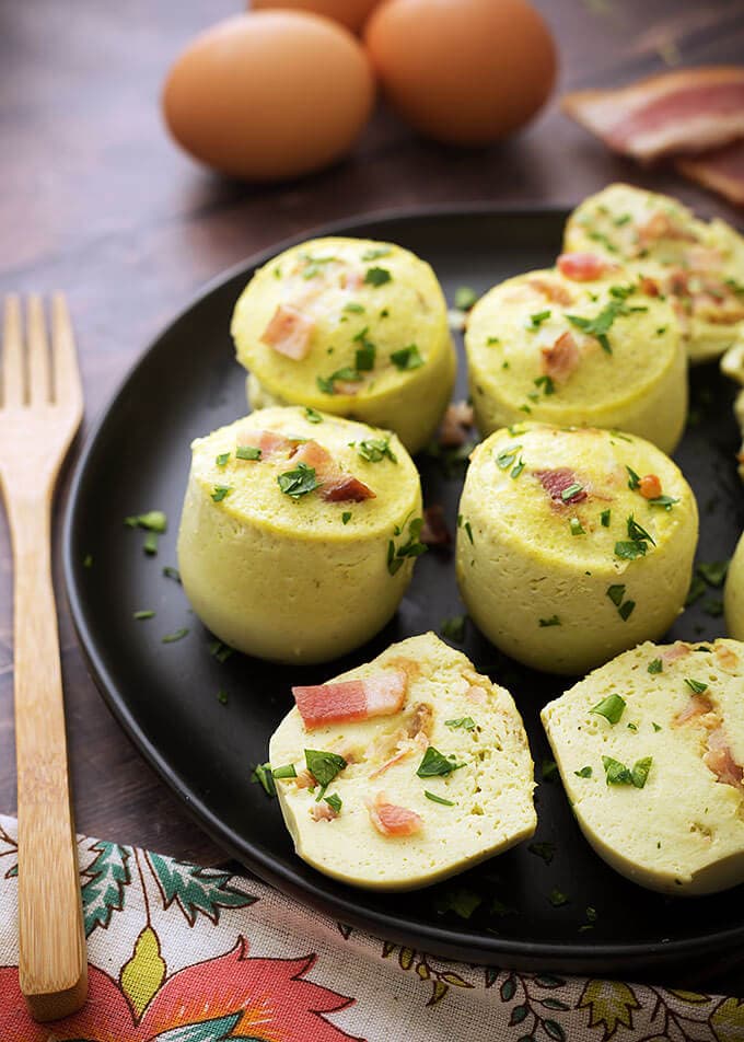 Several Egg Bites on a black plate next to a wooden fork