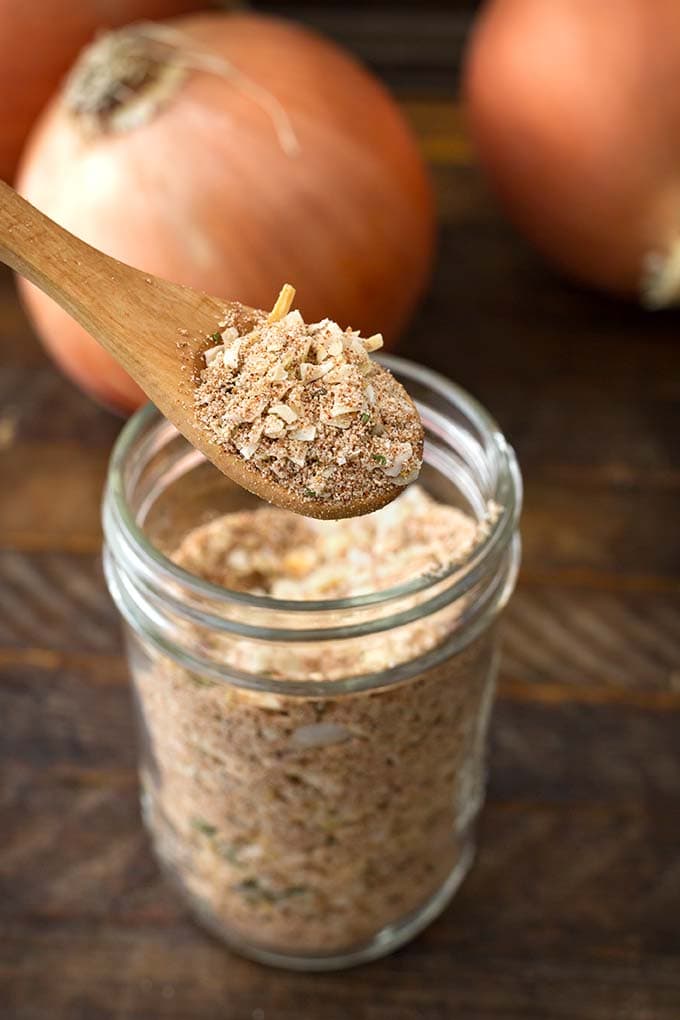 Closeup of wooden spoon scooping up Homemade Onion Soup Mix from a small glass jar