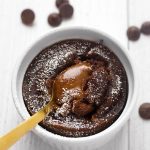 Chocolate Lava Cake in a white ramekin with golden spoon all on a light colored background