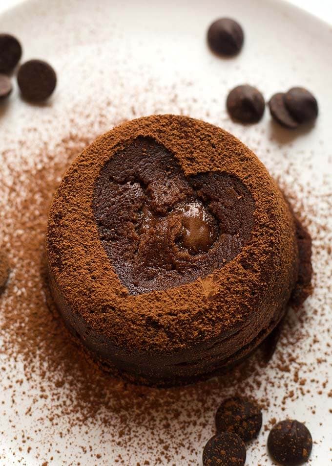 Chocolate Lava Cake with cocoa powder dusted heart all on a white plate with chocolate chips