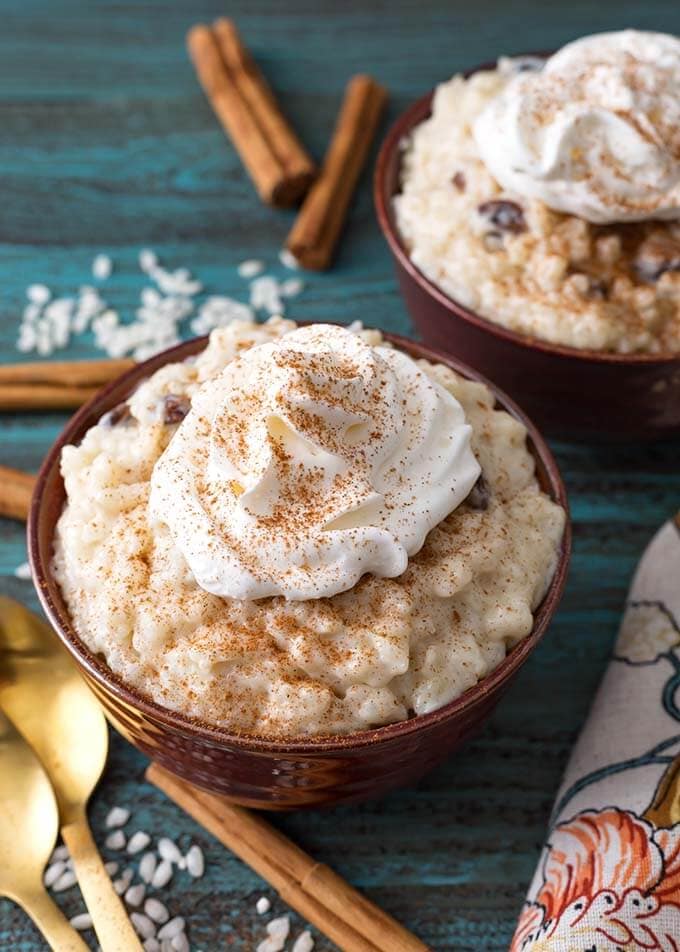 Closeup of Rice Pudding in a brown bowl topped with whipped cream