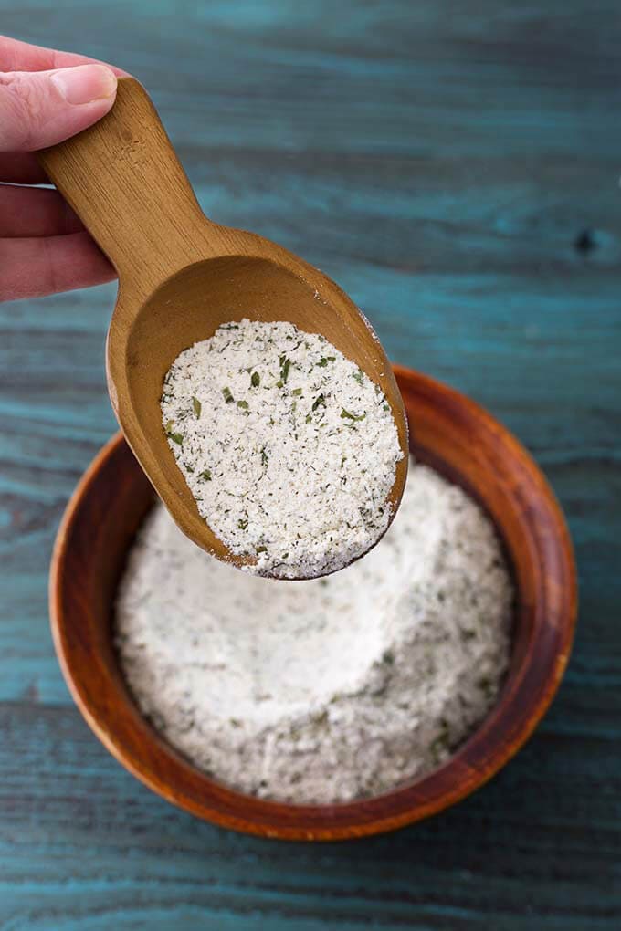 Small wooden scoop showing Homemade Ranch Dressing Mix over bowl of rest of mix