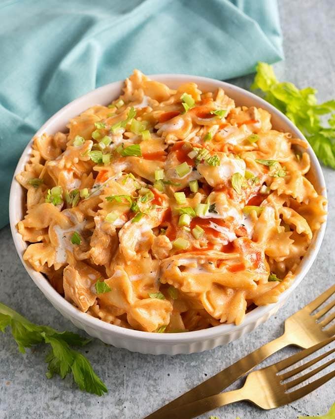 Buffalo Chicken Pasta in a white bowl next to two gold forks