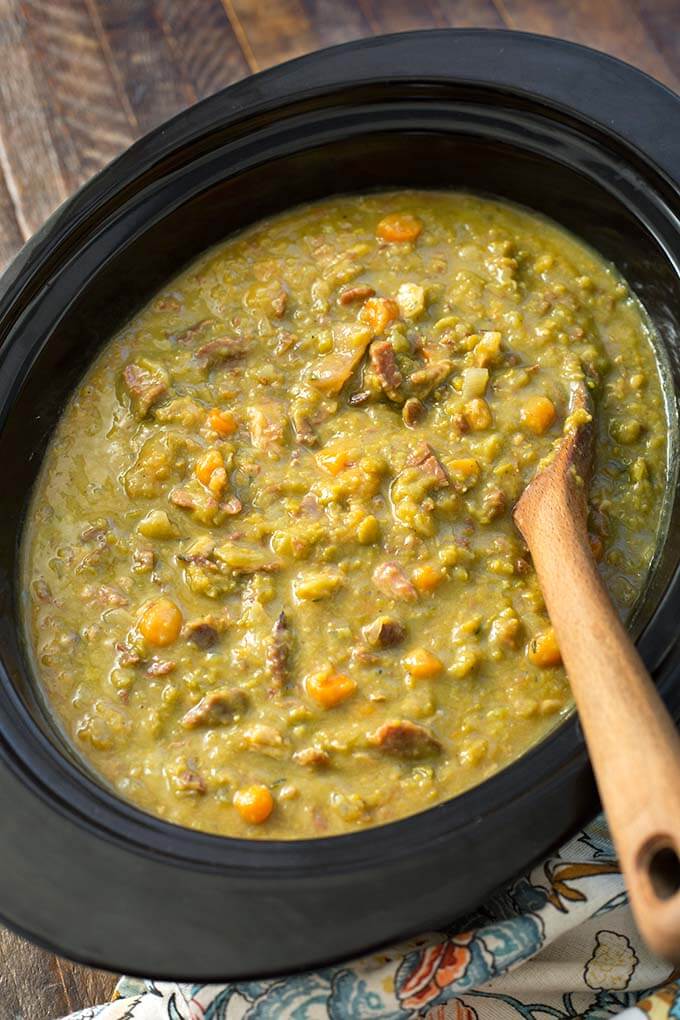 Top view of Split Pea Soup in a slow cooker with wooden mixing spoon