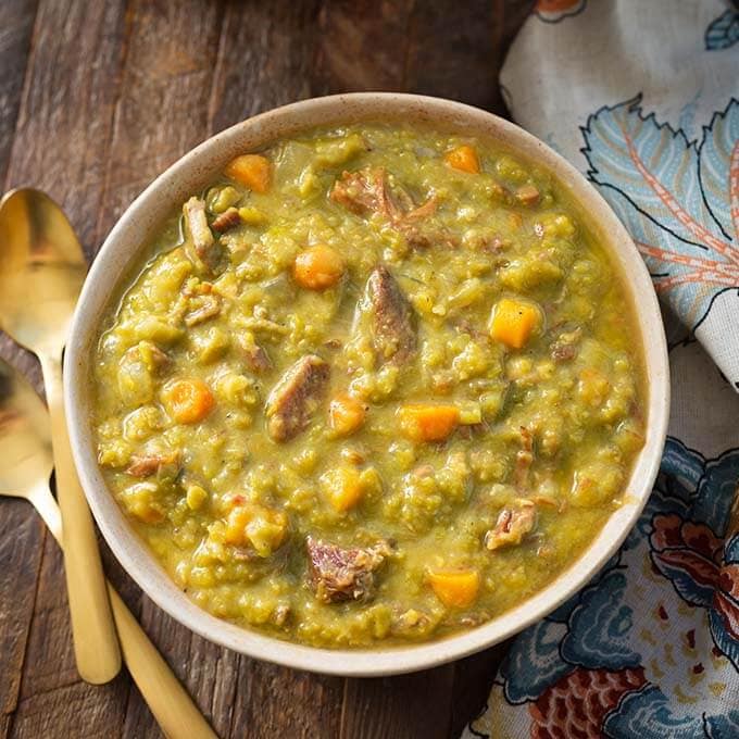 Split Pea Soup in a beige bowl next to two golden spoons