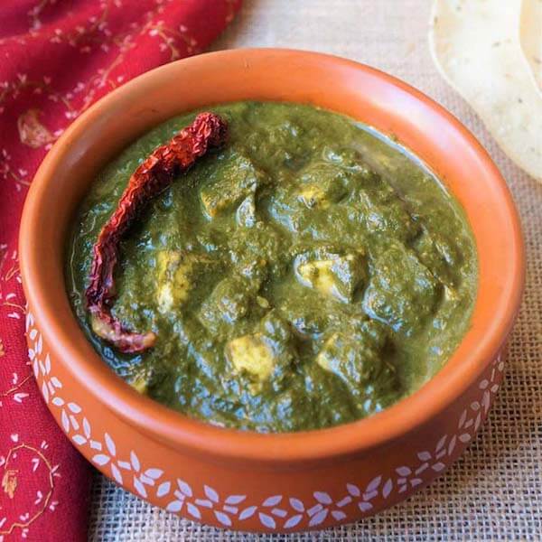 Palak Paneer in a orange bowl with white pattern