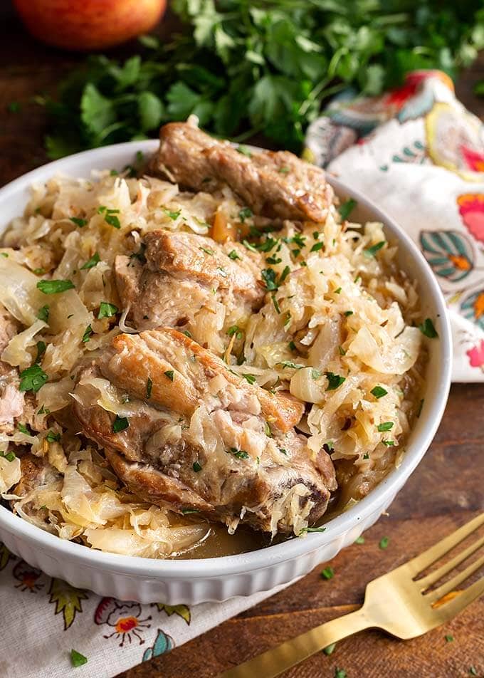 Pork and Sauerkraut in a white bowl next to a gold fork