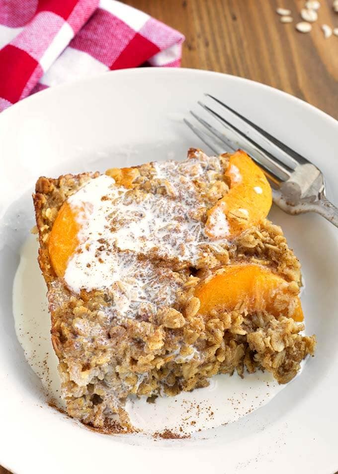 Slice of Easy Peach Baked Oatmeal on a white plate with a silver fork