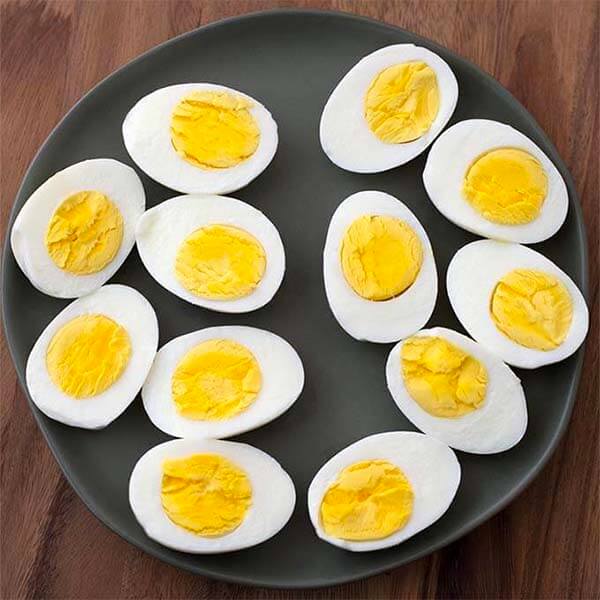 several boiled eggs sliced in half on a black plate