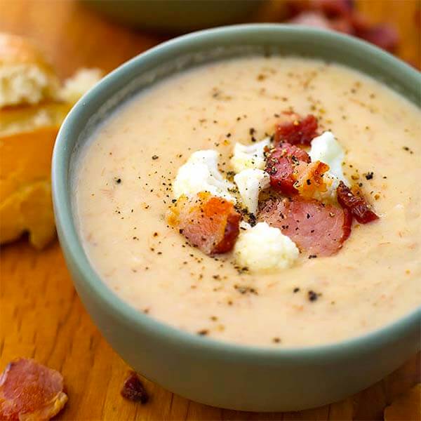cauliflower bacon chowder in a green bowl topped with bacon pieces and cauliflower
