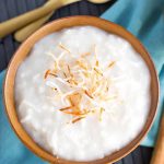 Coconut Rice Pudding in a brown bowl topped with toasted coconut.