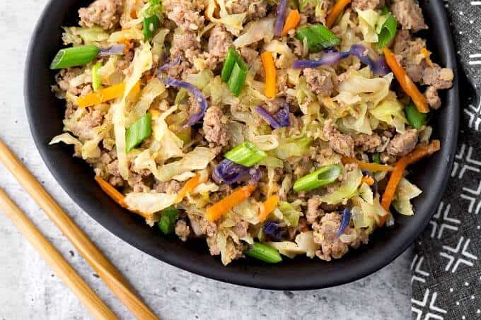 Egg Roll in a Bowl in a black bowl next to two bamboo chopsticks