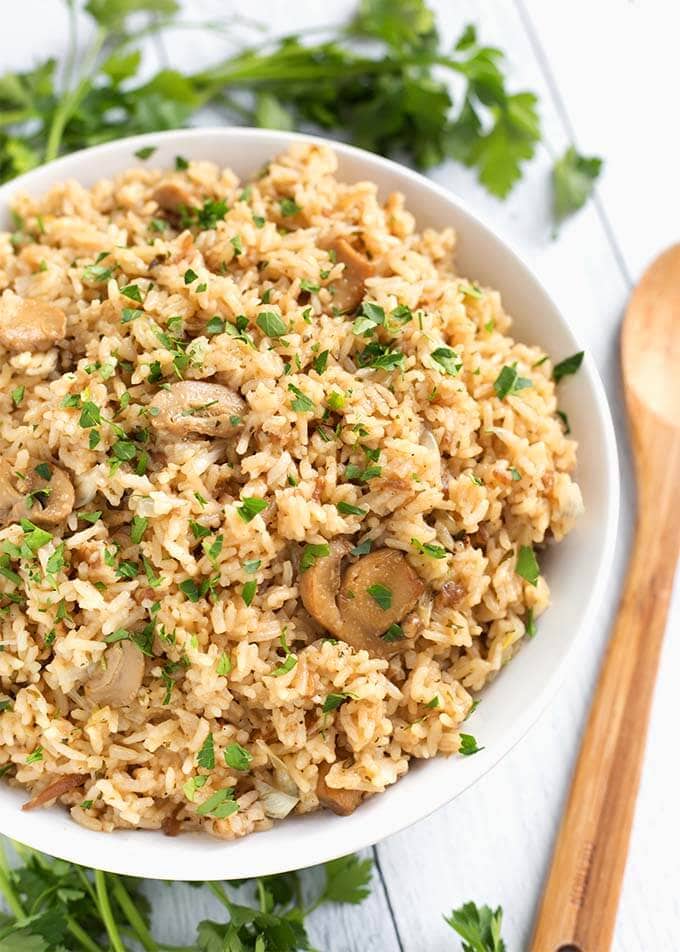 Top view of French Onion Rice in a white bowl next to a wooden spoon