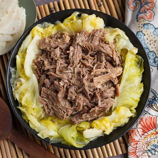 kalua pork over cooked cabbage in a black bowl
