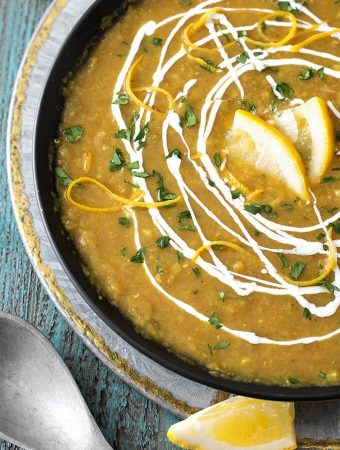 Red Lentil Curry Soup in a black bowl on a silver plate
