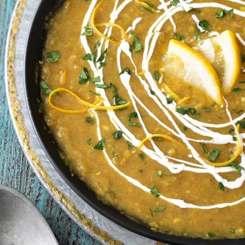 Red Lentil Curry Soup in a black bowl on a silver plate