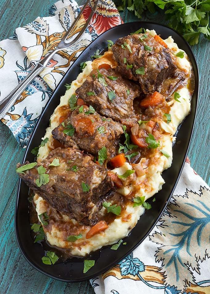 Top view of Short Ribs over mashed potatoes on an oblong black plate