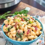 Tuscan Chicken Pasta in a blue bowl in front of a pressure cooker