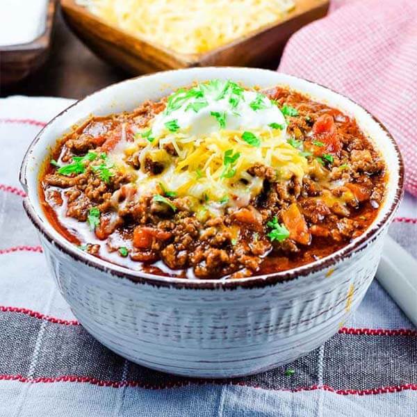 keto low carb beef chili in a white bowl topped with melted cheese and sour cream