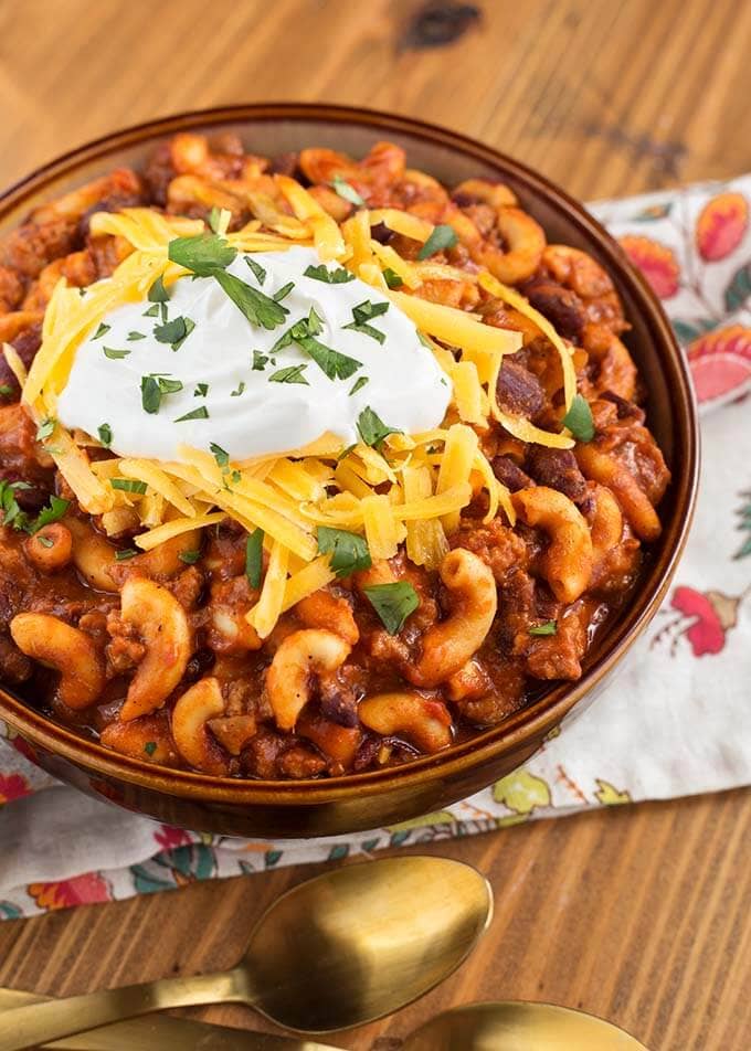 Chili Mac topped with cheese and sour cream in a brown bowl