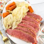 Sliced Corned Beef and Cabbage with carrots on an oblong white plate