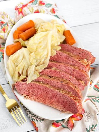 Sliced Corned Beef and Cabbage with carrots on an oblong white plate