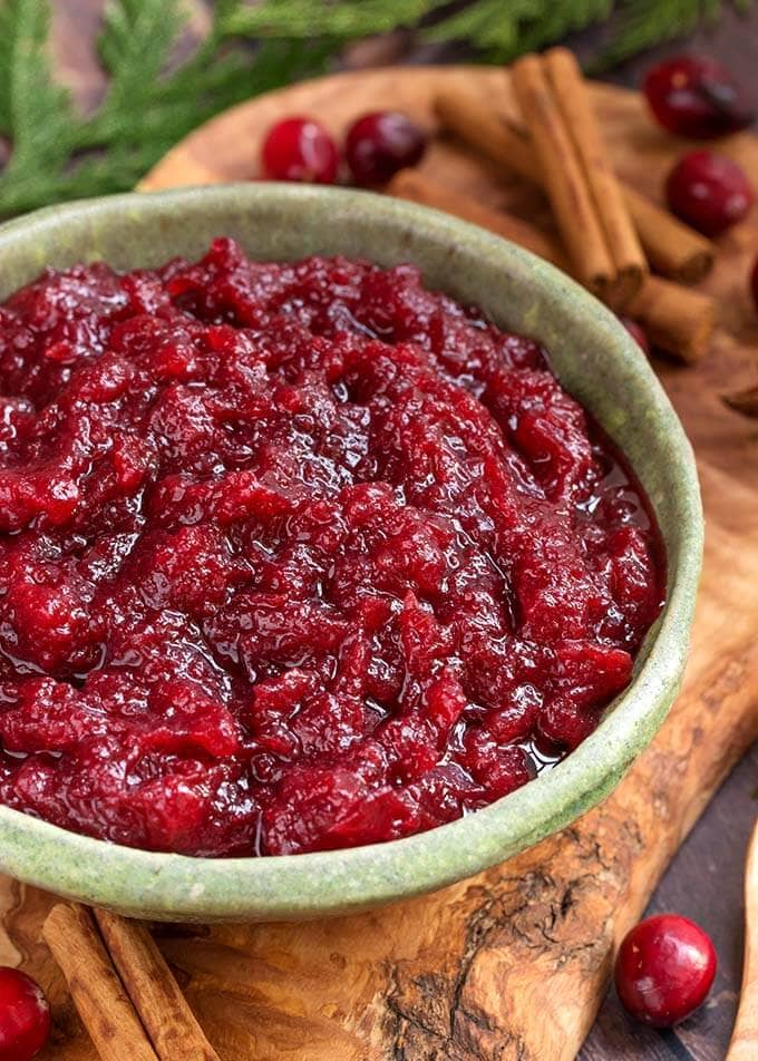 Cranberry Sauce in a green bowl on a wooden plank