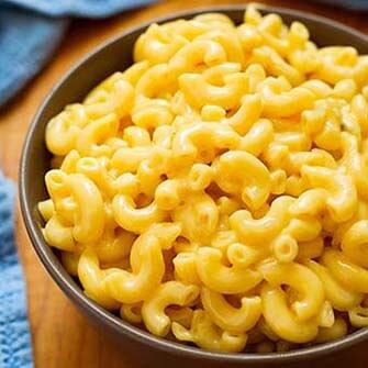 Mac and Cheese in a dark brown bowl on a wooden board