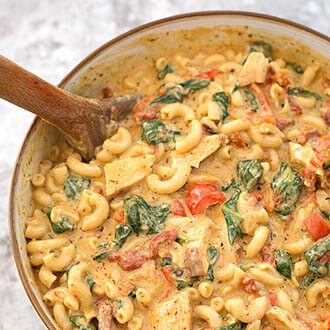 Instant pot creamy garlic tuscan pasta in a brown bowl with wooden mixing spoon