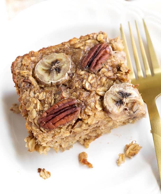 close up of Baked Oatmeal on white dish with gold fork