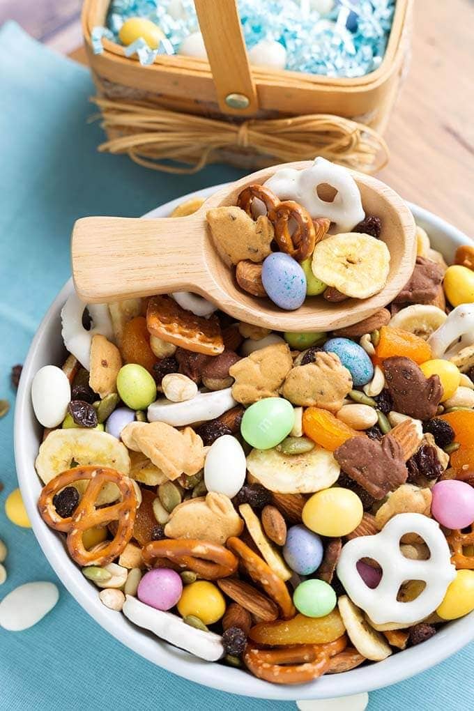 Bunny Bait Easter Trail Mix in a white bowl with wooden serving spoon in front of small basket