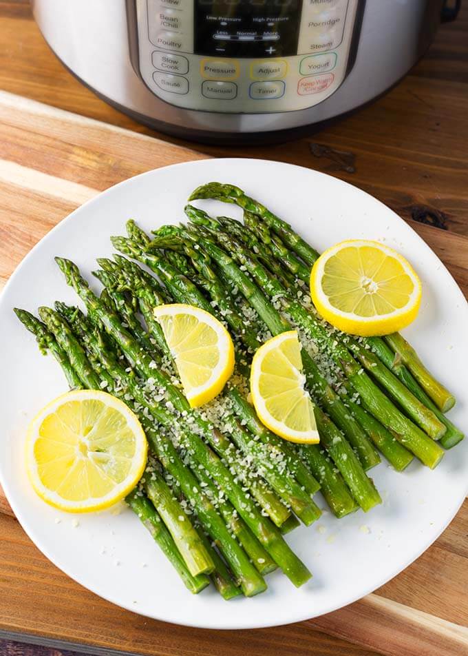 Asparagus with lemon slices on a white plate