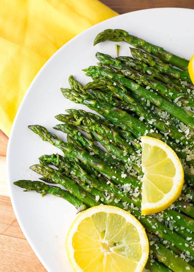 Close up of Asparagus on white plate with lemon