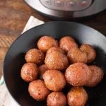 Baby Potatoes on a black plate in front of a pressure cooker