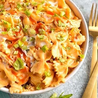 instant pot buffalo chicken pasta in a white bowl next to golden forks