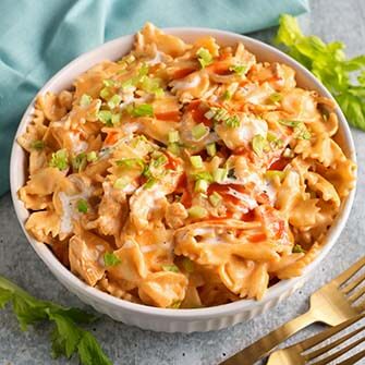 buffalo chicken pasta in a white bowl next to two golden forks