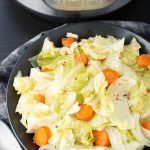 Cabbage Side Dish in a black bowl in front of a pressure cooker