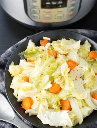 Cabbage Side Dish in a black bowl in front of a pressure cooker