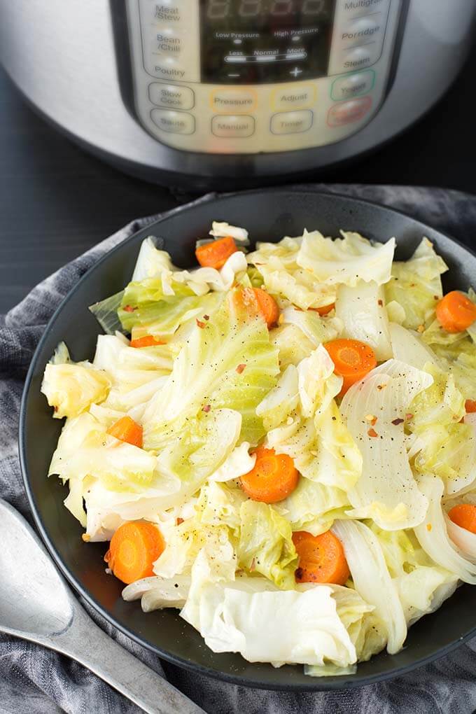 Cabbage Side Dish in a black bowl in front of a pressure cooker