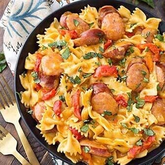 cajun pasta on a black plate next to two golden forks