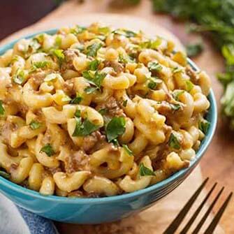 cheeseburger macaroni in a turquoise bowl on a wooden board