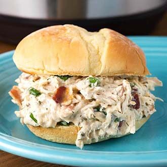 Instant Pot Crack Chicken on a hamburger bun on a blue plate