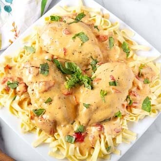 instant pot creamy cajun chicken breasts over noodles on square white plate