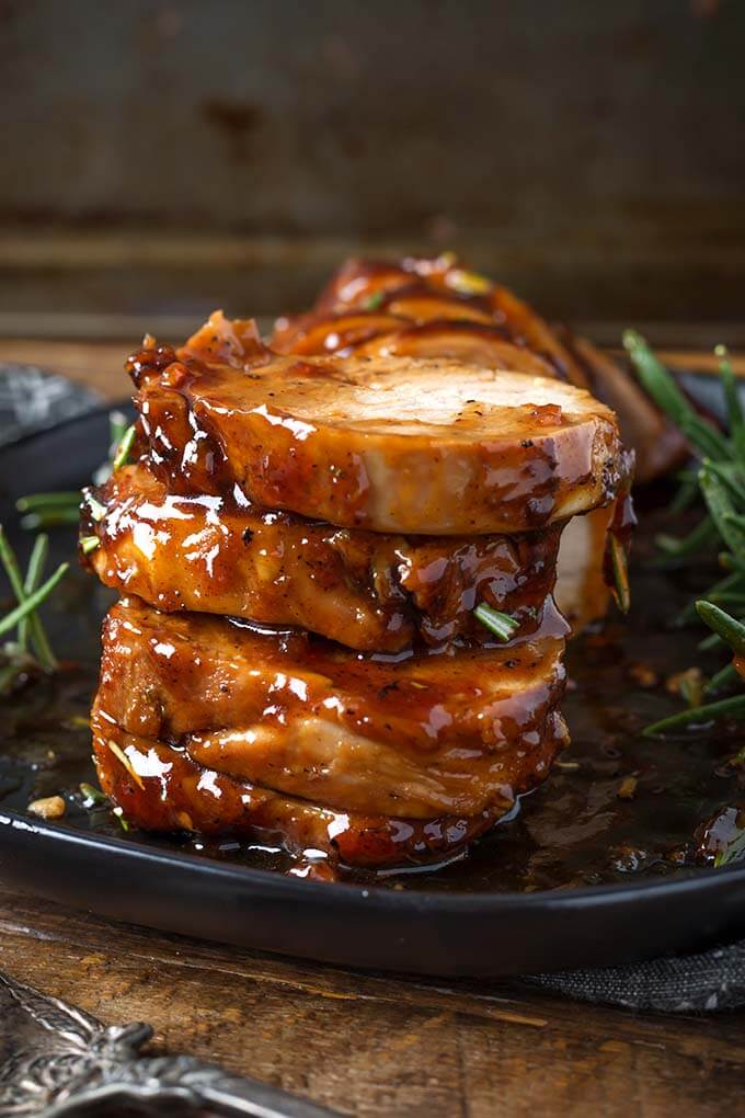 Stacked sliced Honey Garlic Pork Tenderloin on black plate