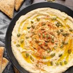 Hummus in black bowl next to cut pieces of flatbread