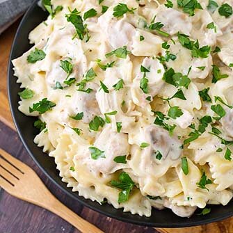 leftover turkey pasta on a black plate next to a wooden fork