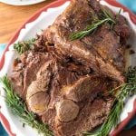 Leg of Lamb on red bordered plate garnished with rosemary