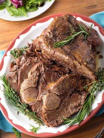 Leg of Lamb on red bordered plate garnished with rosemary